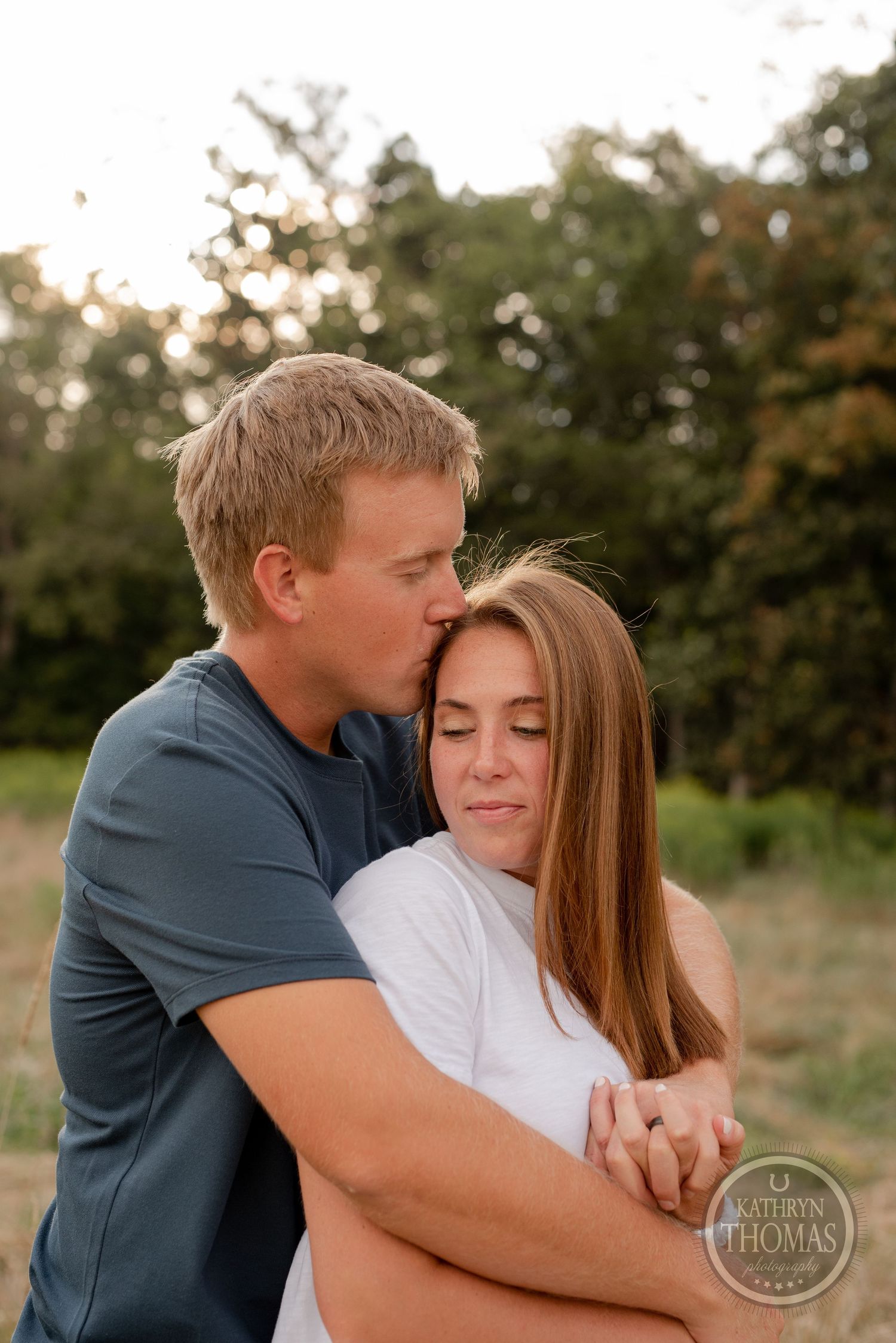 A gentle embrace captured in warm evening light with a natural outdoor setting.