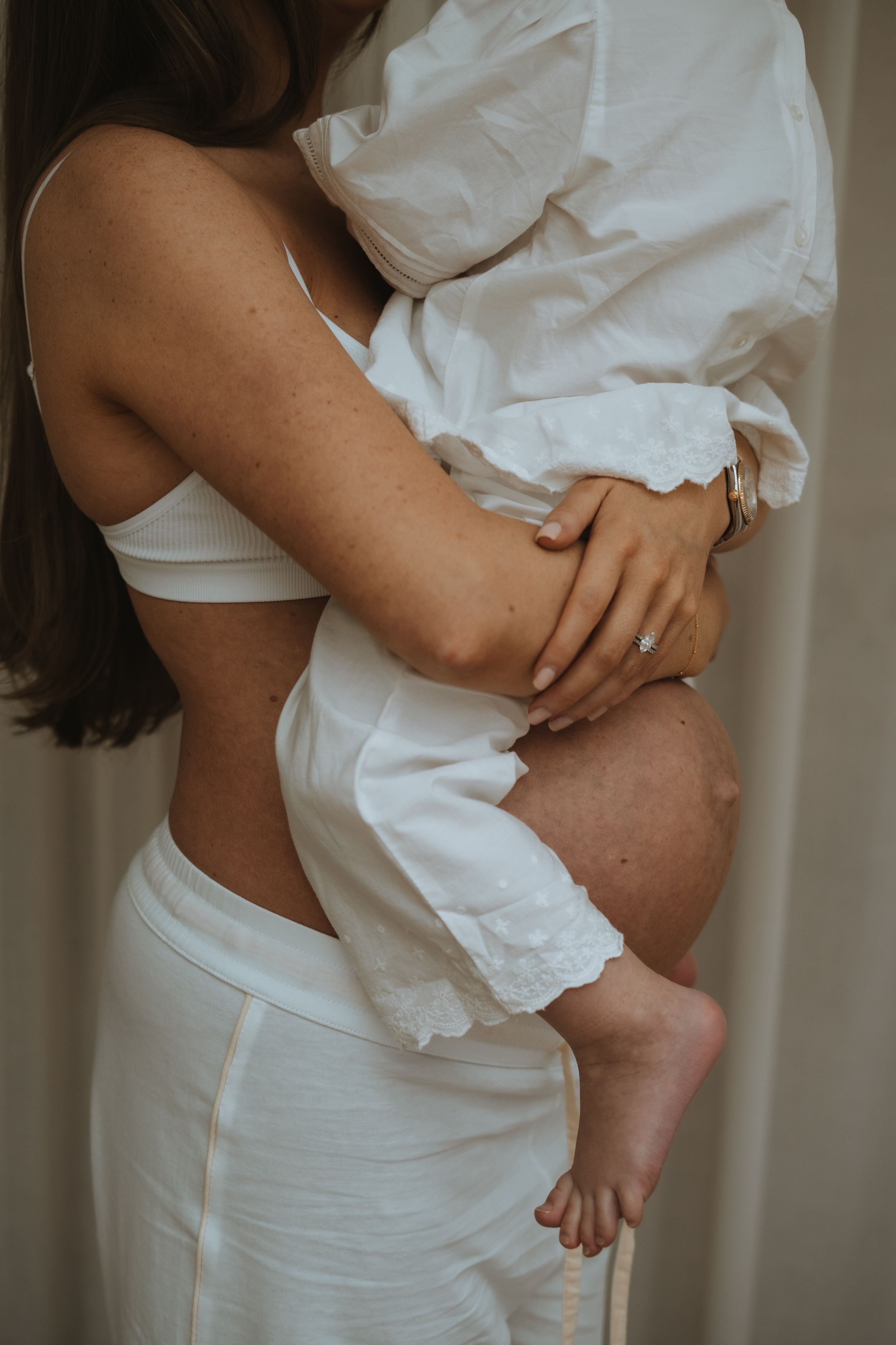 minimalist aesthetic photograph of mother holding toddler over bump