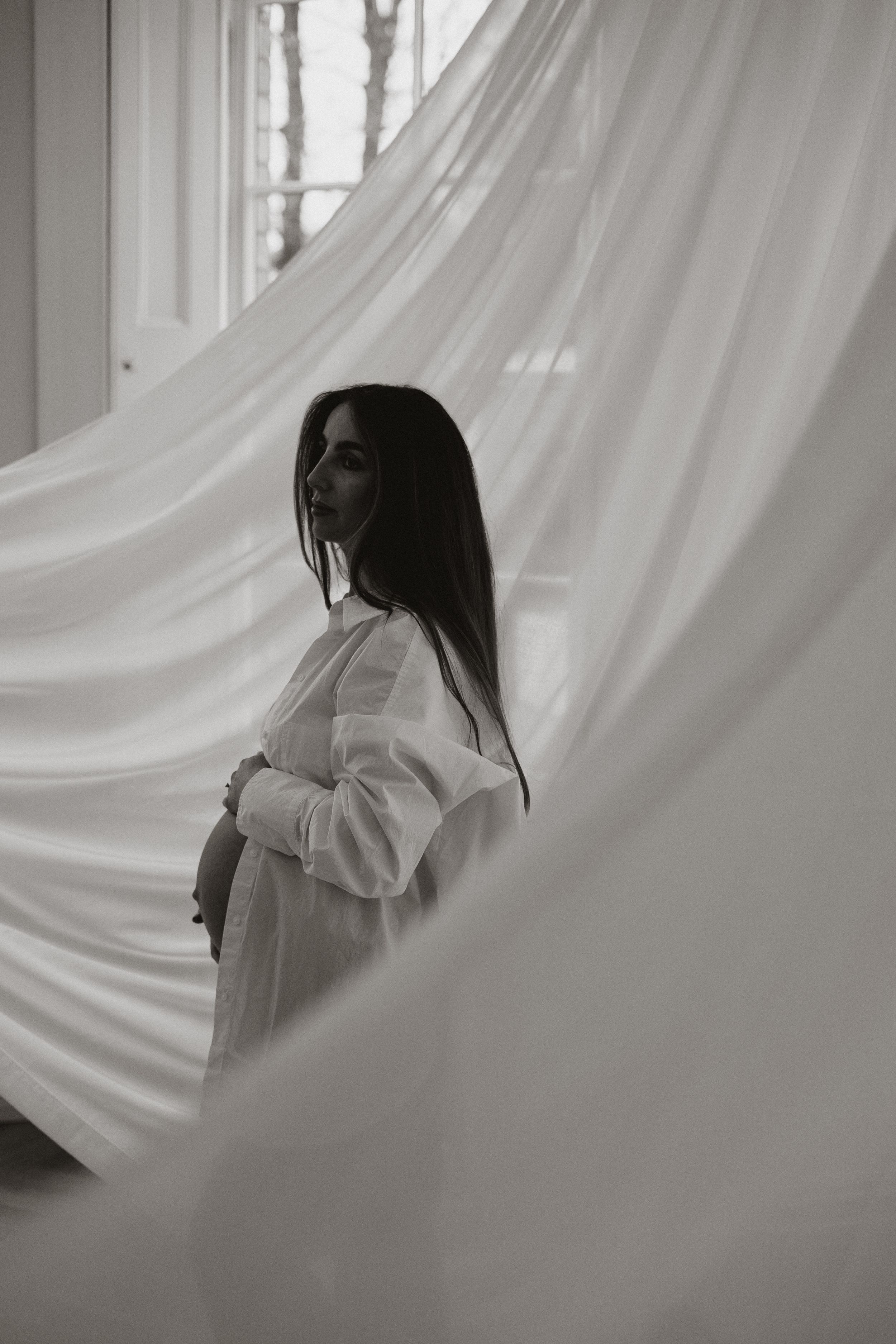 minimalist aesthetic photograph of mother holding bump with fabric installation