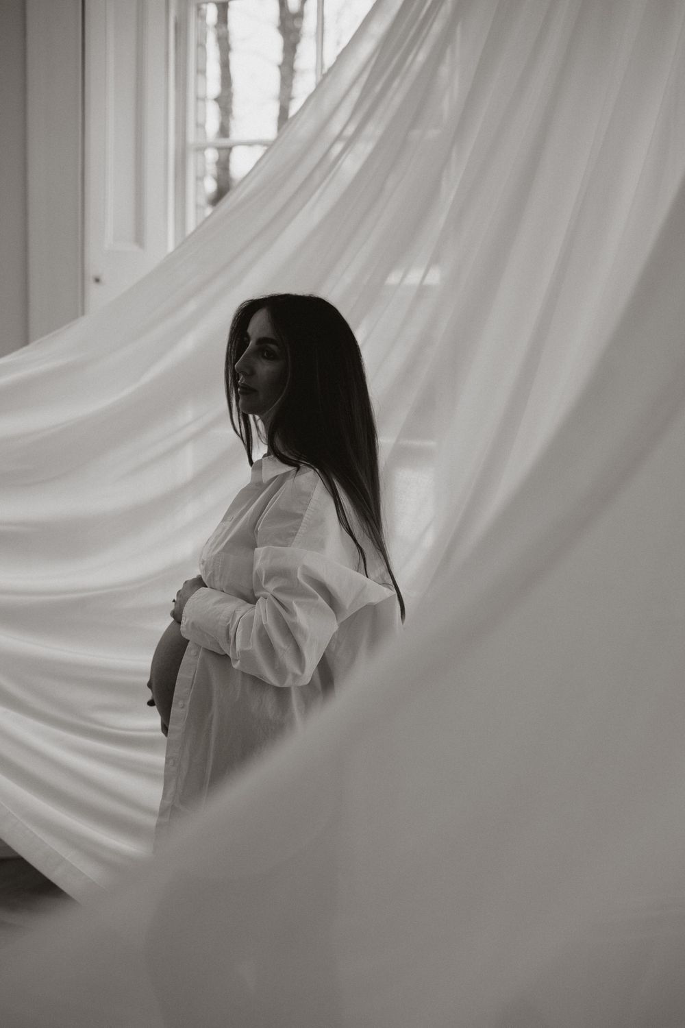 minimalist aesthetic photograph of mother holding bump with fabric installation