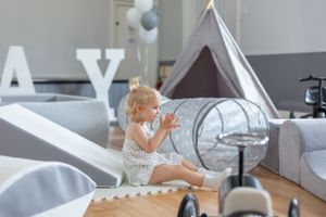 A playroom setup with teepee tent, toys, and modern decor in neutral gray tones.