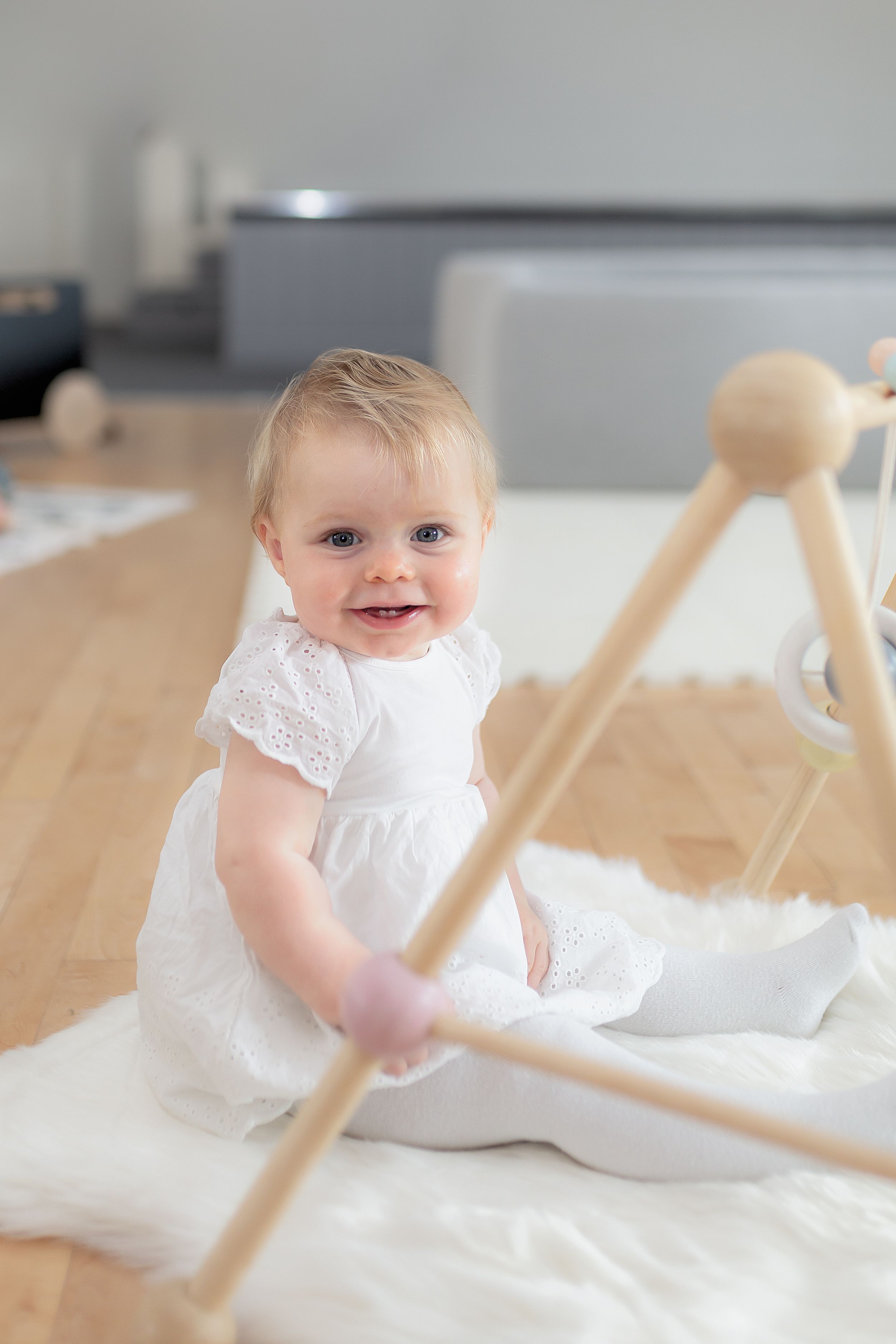 A sweet moment of playtime on a white blanket with wooden toys in a modern living space.