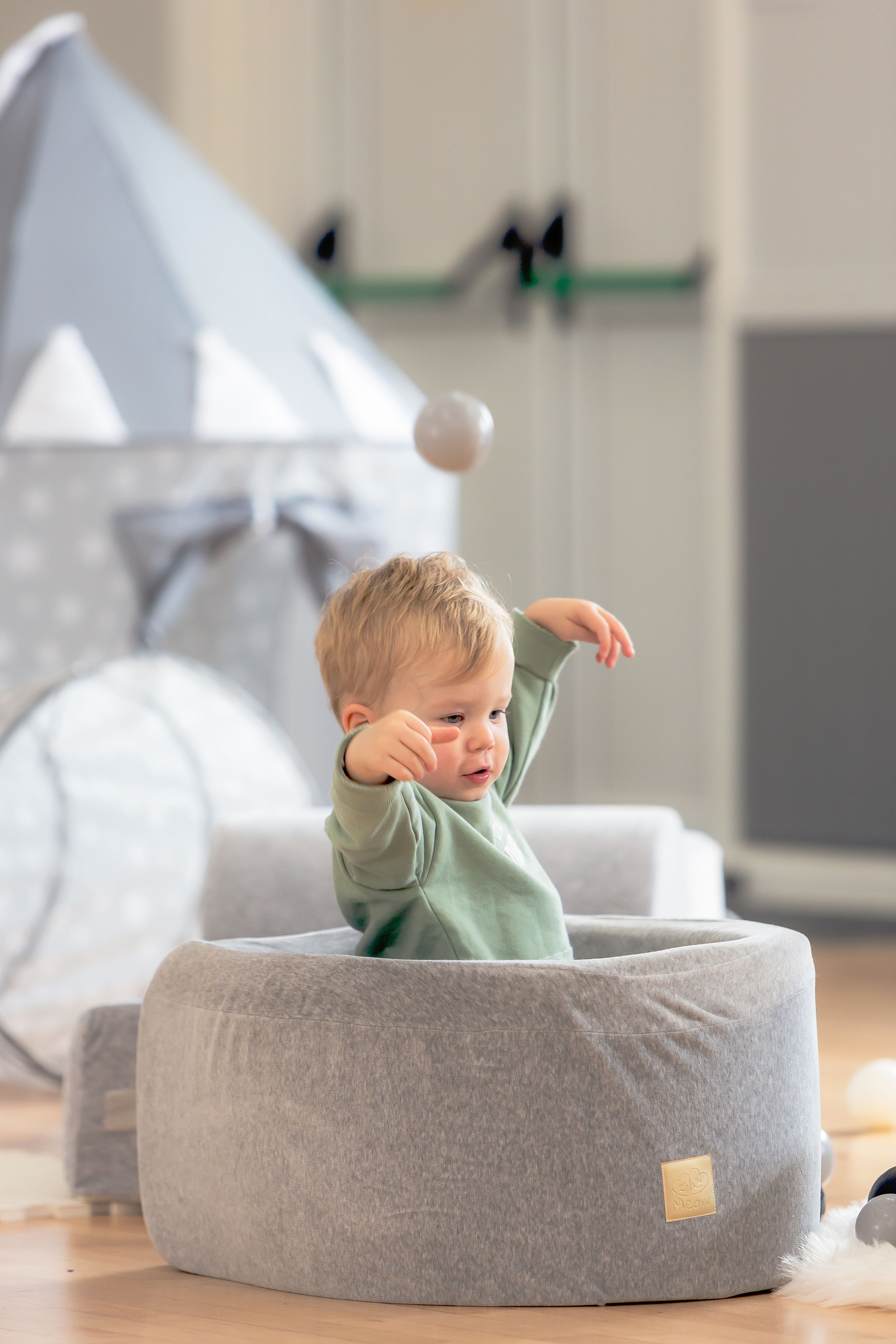 Small child sitting in round gray cushioned seat.