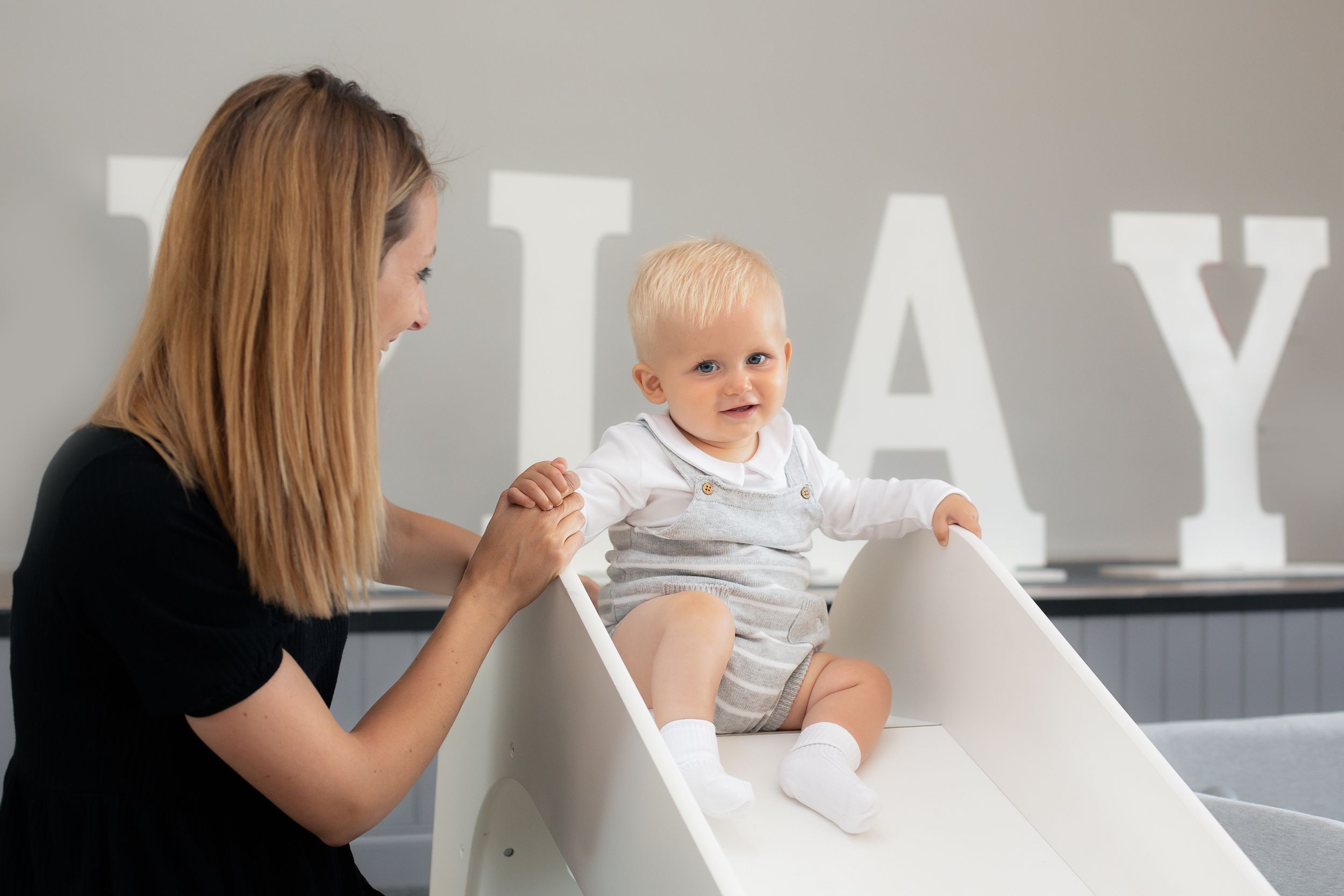 Caregiver helping child on changing table with white letters on wall.