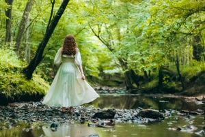 Storytelling travel photo of a dancer in a white dress on rocks while looking over a creek in Charlotte, North Carolina