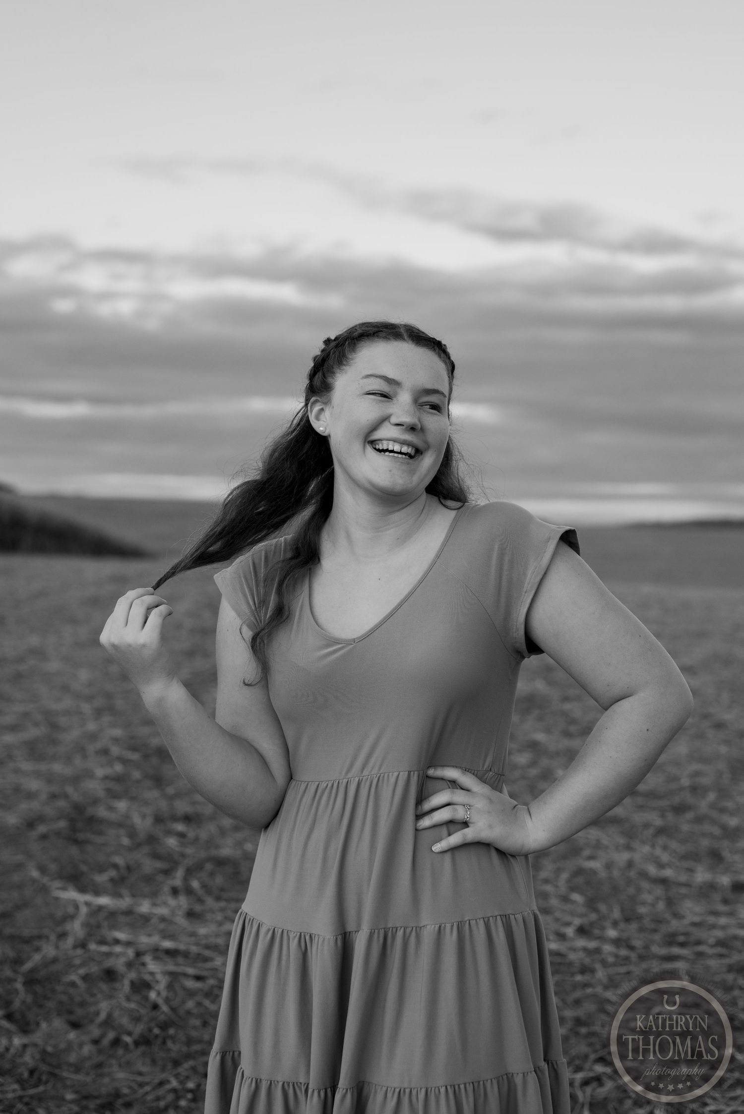 Black and white portrait showing joyful expression in a tiered dress at sunset.