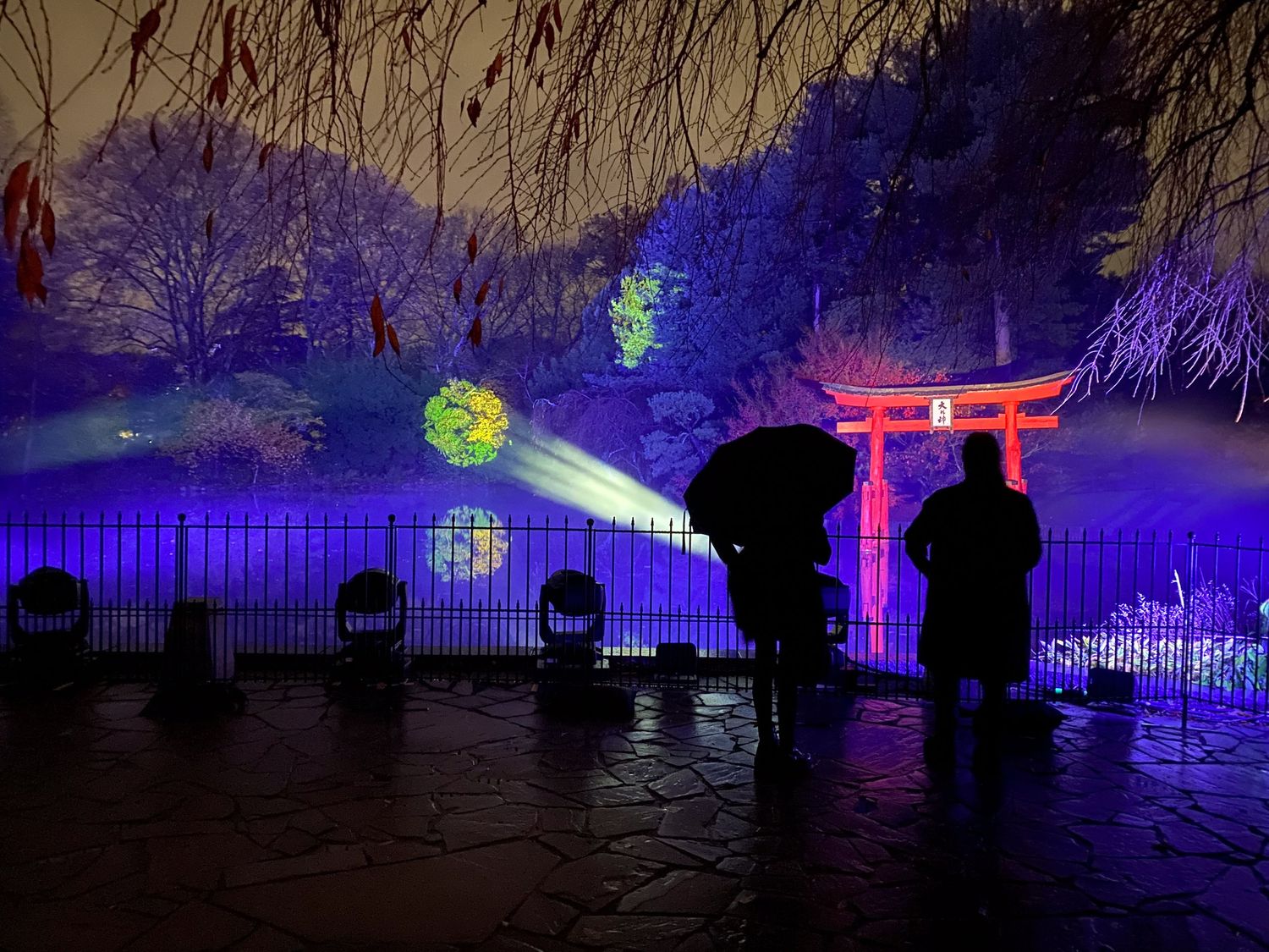 Japanese torii gate illuminated in dramatic blue and red lights with glowing orbs.