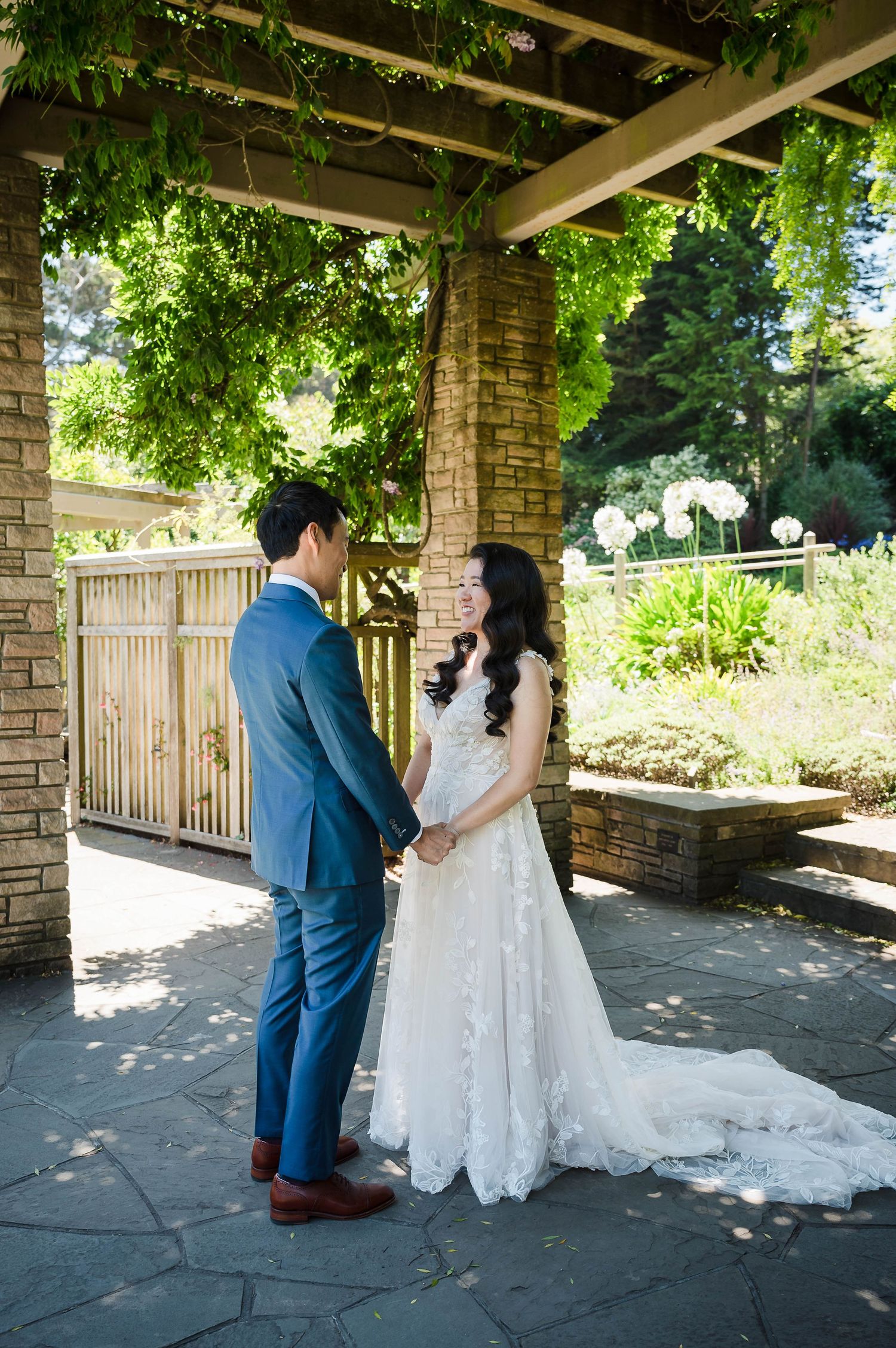 A romantic moment captured under a covered brick walkway adorned with hanging vines.