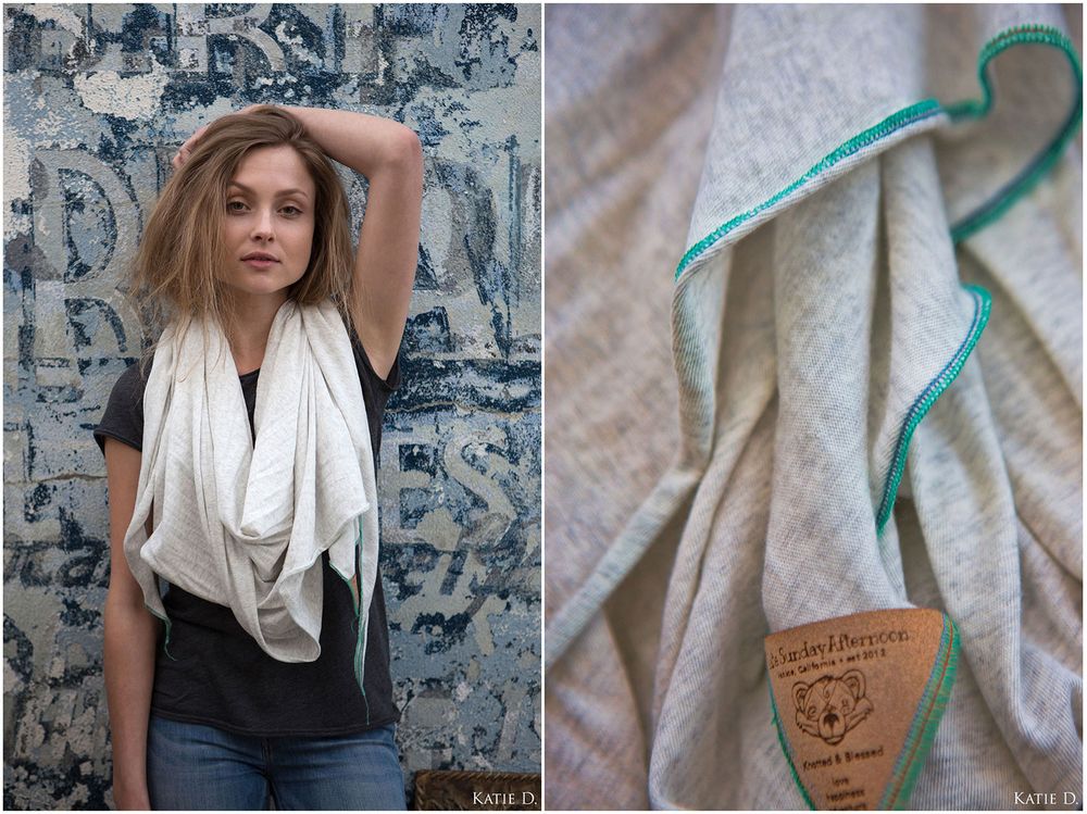 Woman wearing a cream infinity scarf with teal stitched edges and handmade label tag.