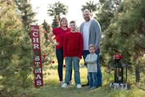 Holiday portrait with Christmas decorations and pine trees in outdoor setting.