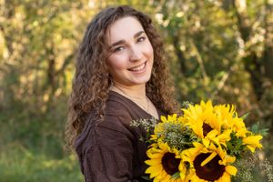 A candid autumn portrait with bright sunflowers and warm natural lighting in an outdoor setting.
