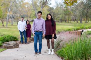 Family walking along a landscaped path wearing coordinated burgundy and pink outfits.