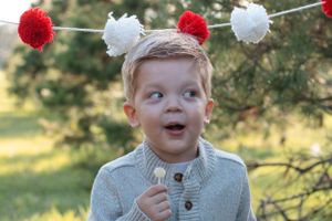 Close-up portrait with festive red and white pom pom garland decorations.