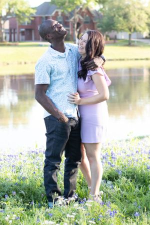 Couple enjoying a romantic moment by a lake with blooming bluebonnets in the foreground.