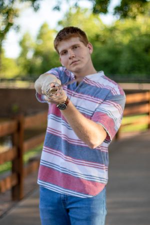 Someone in a striped polo shirt points forward while standing on a wooden deck.