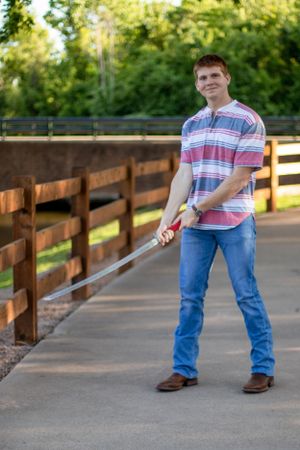 A person stands on a wooden deck pathway holding a baseball bat.