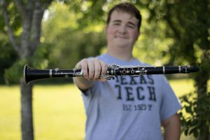 Student holds a clarinet while wearing a Texas Tech shirt outdoors.