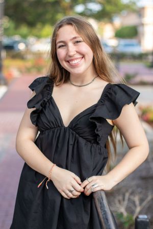 Outdoor portrait in black ruffled dress against urban background.