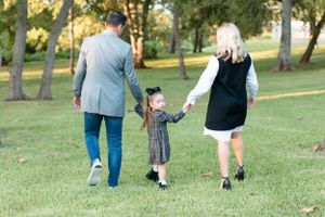 Family walking hand in hand through a park on a sunny afternoon.