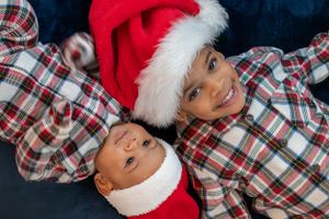 Holiday photo of two wearing matching plaid pajamas and Santa hats.