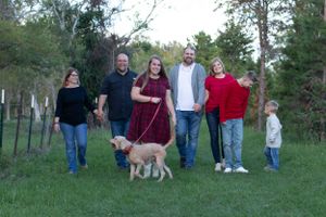 A group stands together in a grassy field with a golden retriever dog on a beautiful evening.