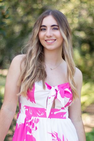 A summer portrait showcasing a white and pink floral dress against a bokeh background.