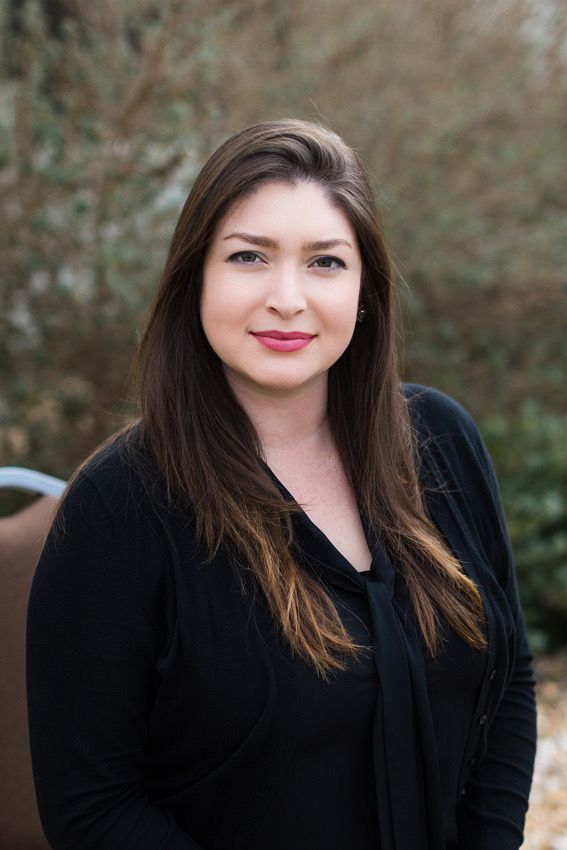 Professional outdoor portrait of person in black top against natural background.