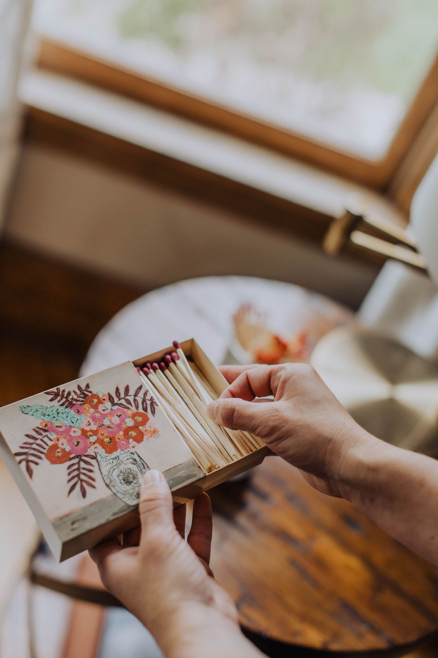 Close-up view of hands holding decorative cards with floral designs on a wooden table.