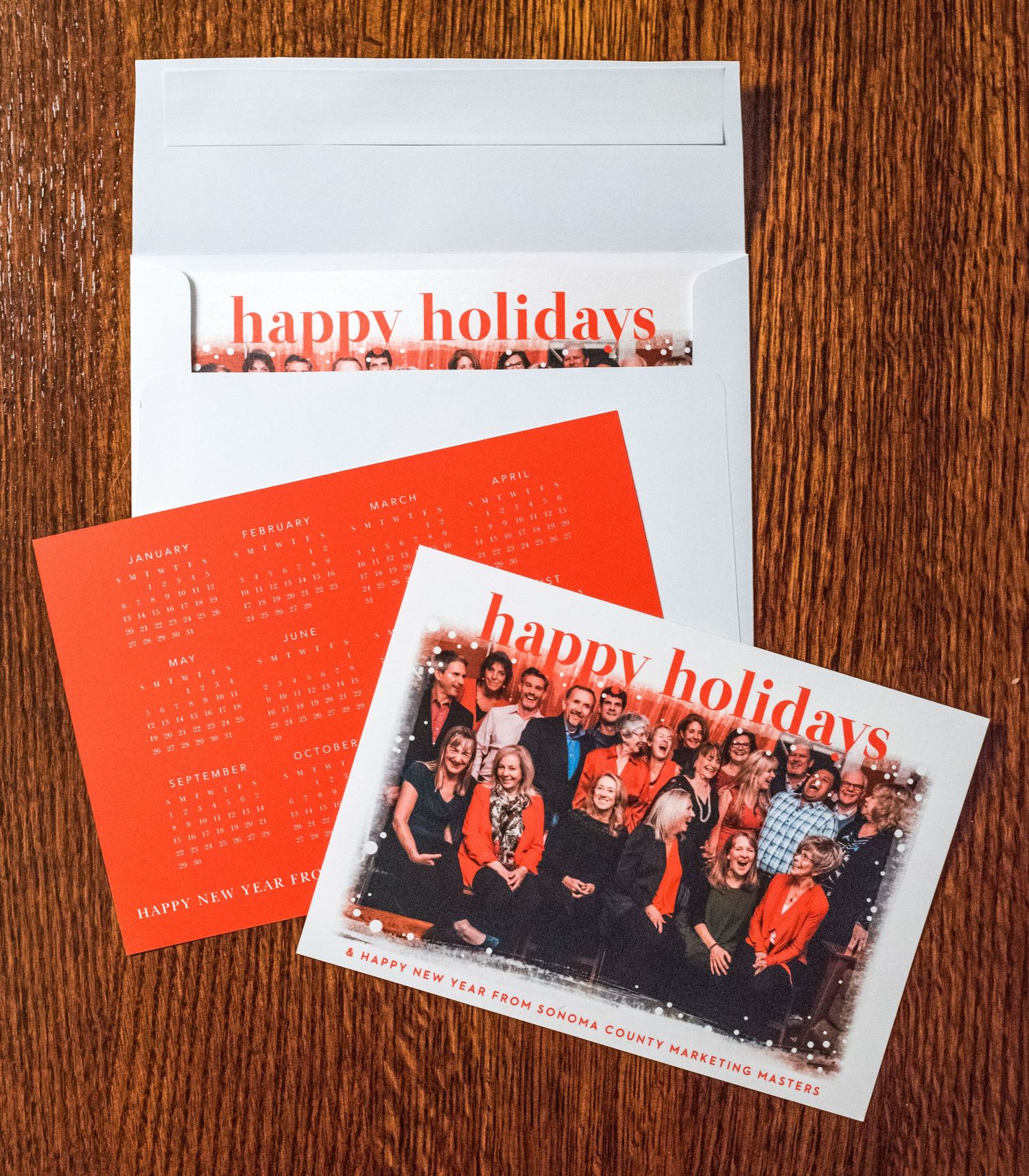 Holiday greeting card with calendar and envelope on wooden surface.