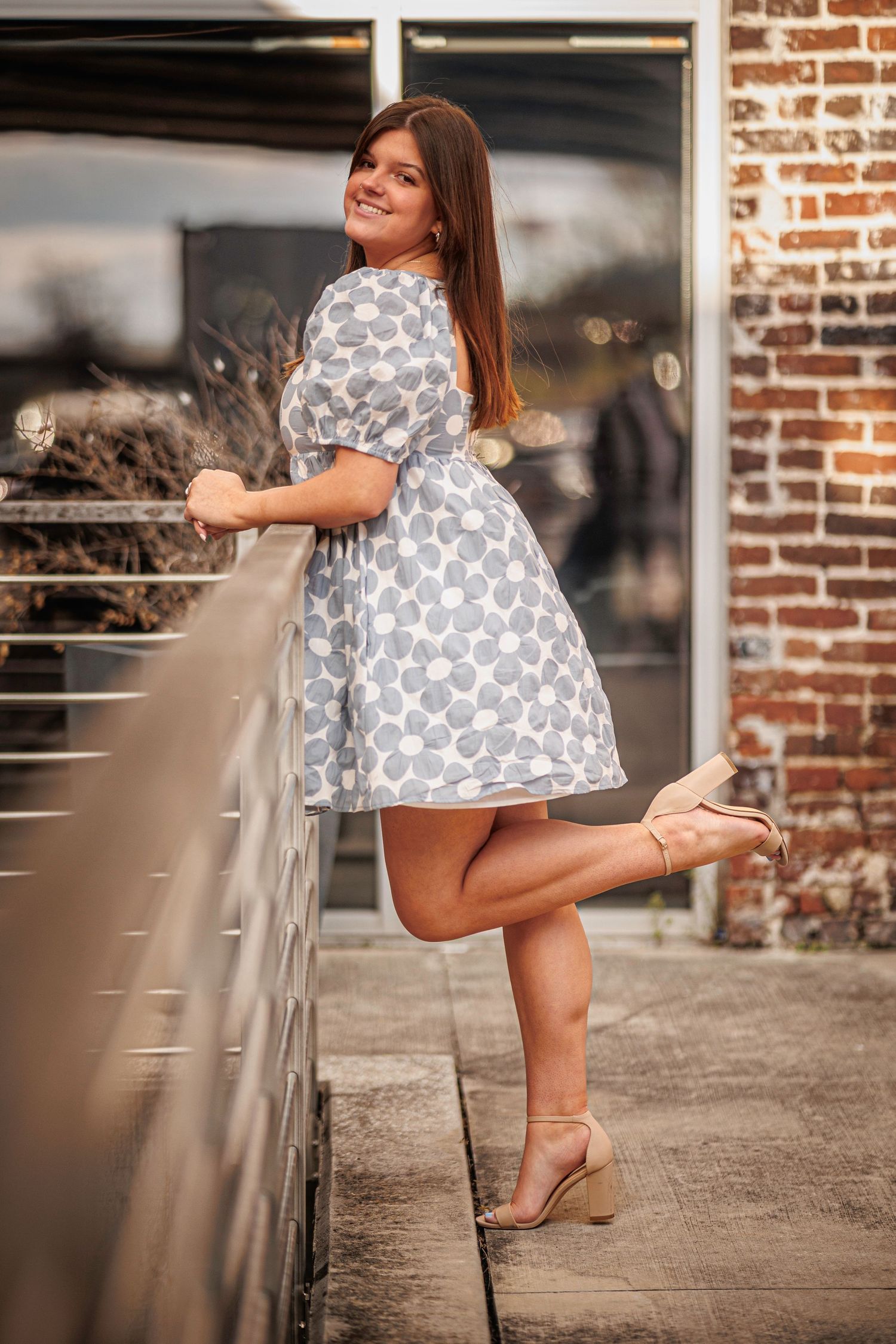 A playful pose in a polka dot dress against a brick wall background.