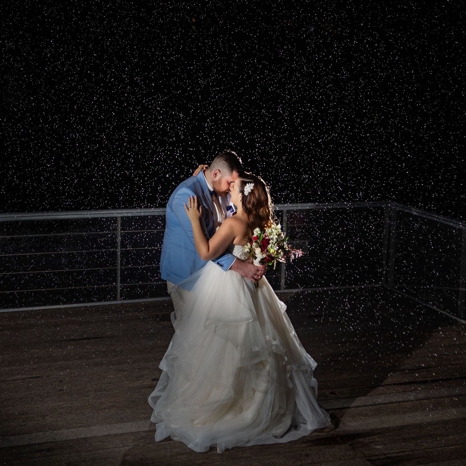 Bride and Groom dancing in the rain at night while the rest of the guest party the night away.