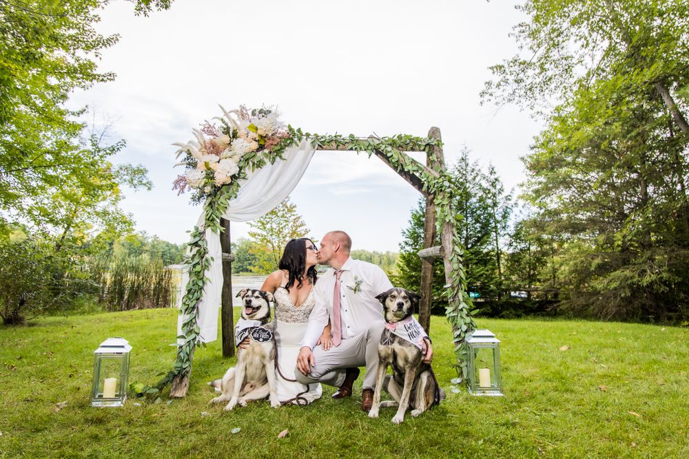 Wedding couple poses in a lush green meadow with decorative lanterns and natural scenery.