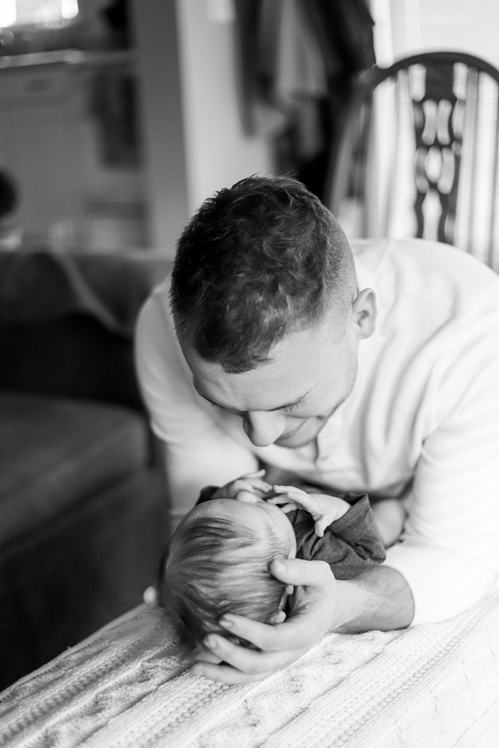 Black and white series showing parent tenderly bonding with newborn on blanket.