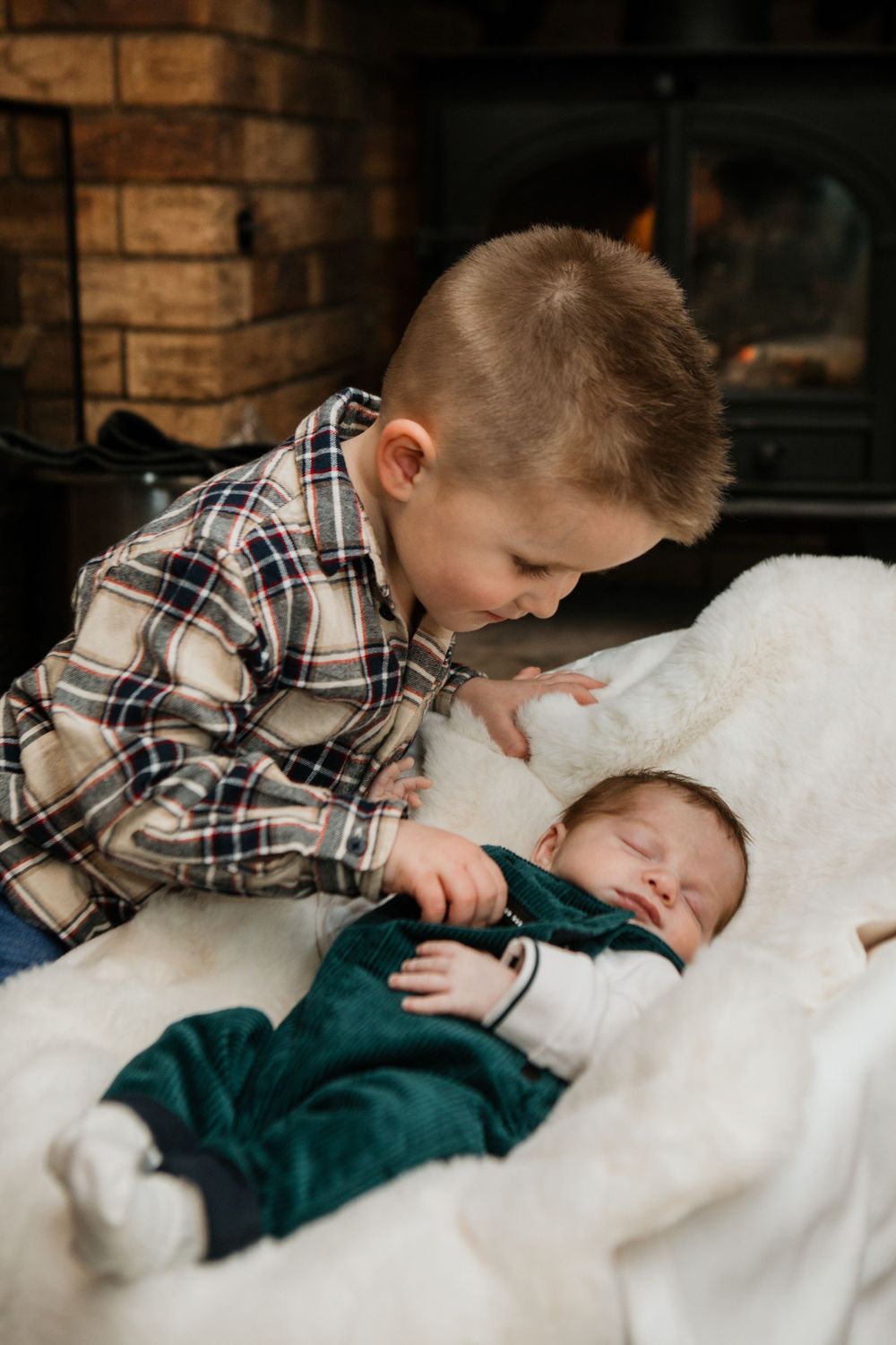 Two siblings share a tender moment by the fireplace during Christmas.