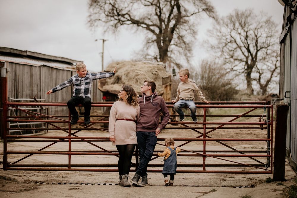 A family enjoying time together by a rustic farm gate on an overcast day.
