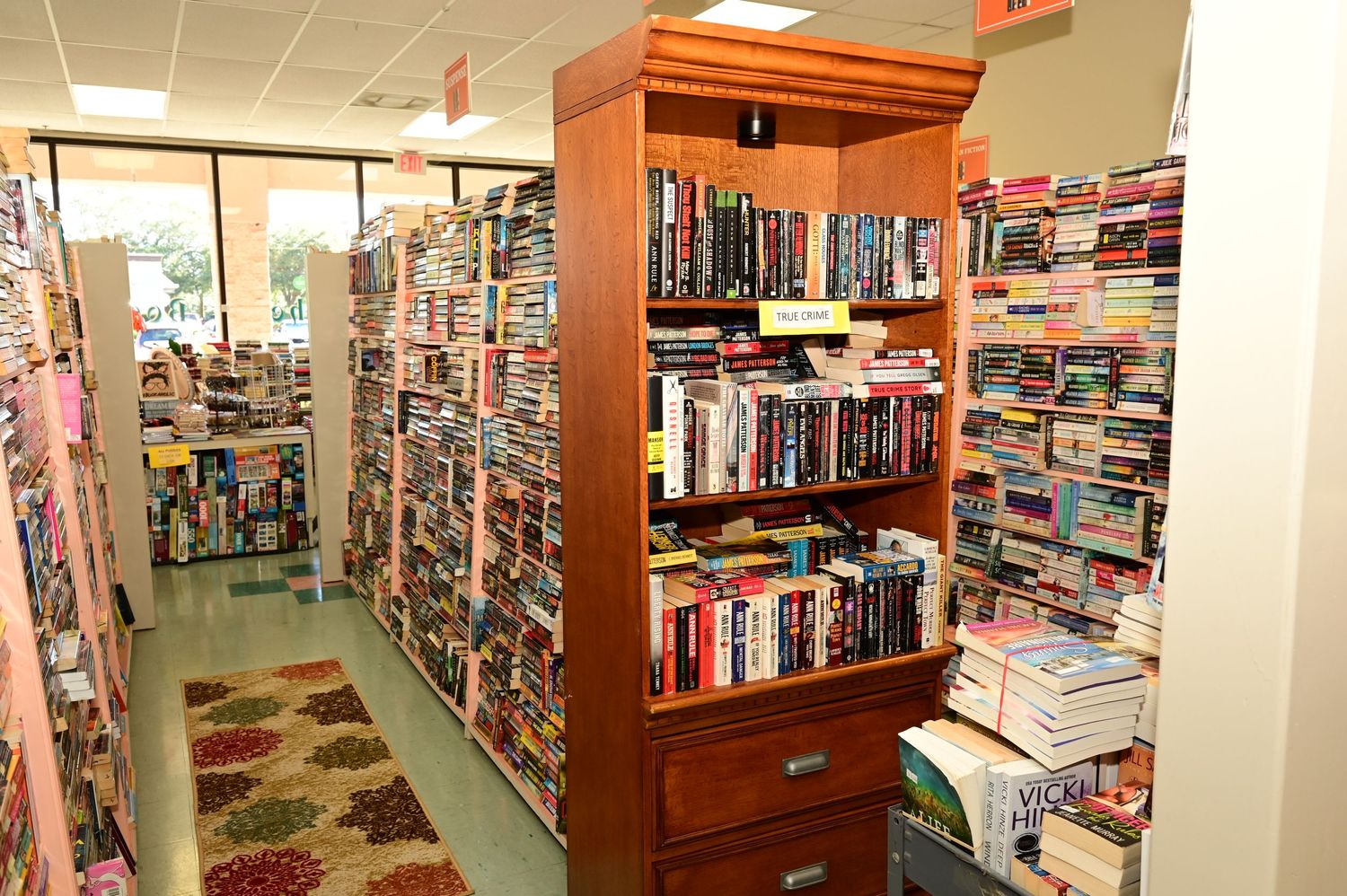 Wide angle view of a bookstore's interior featuring orange wood trim and bright fluorescent lighting.