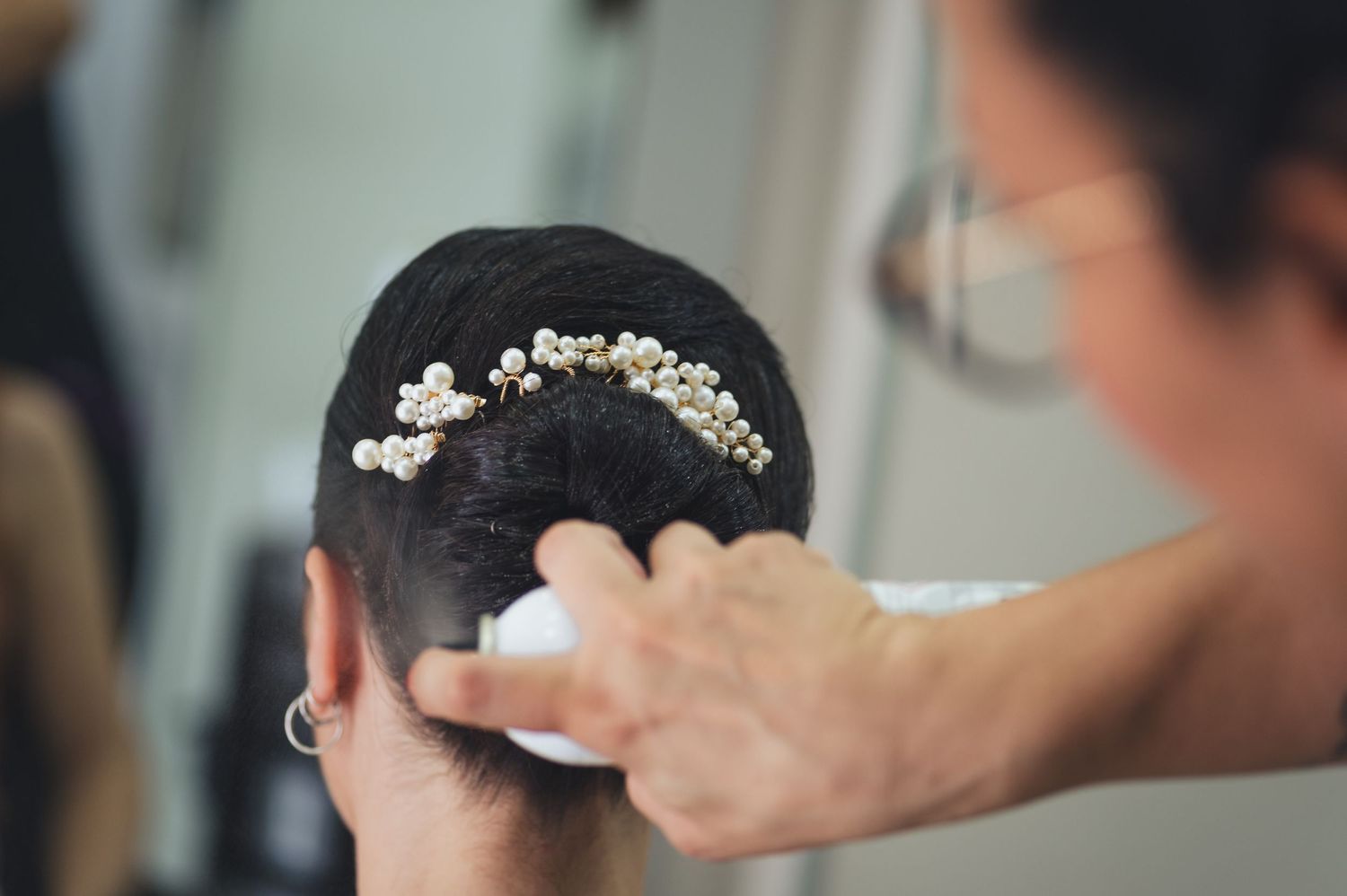A detailed shot of delicate pearl hair accessories being placed during styling.