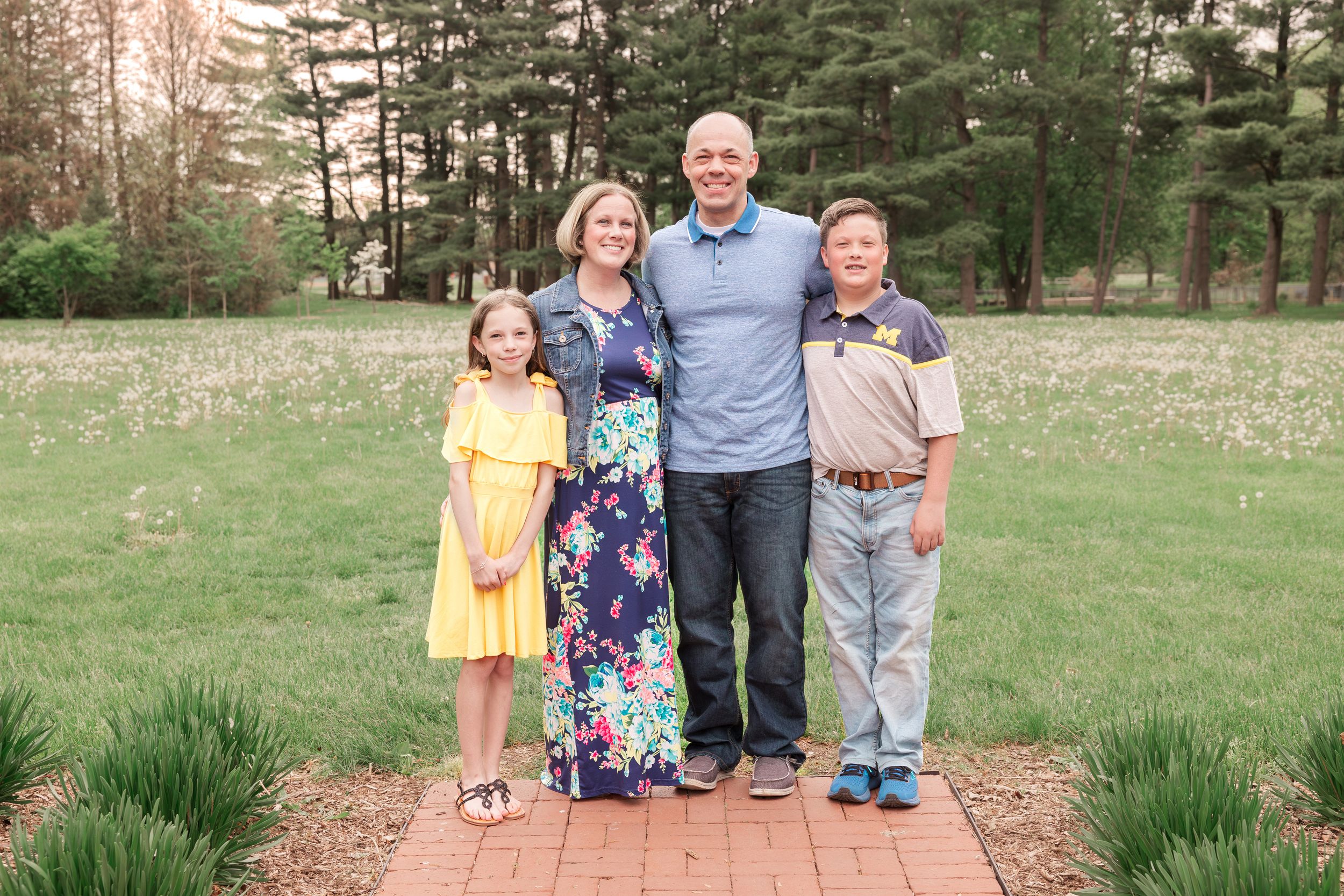 Family portrait on brick pathway with pine trees in background.