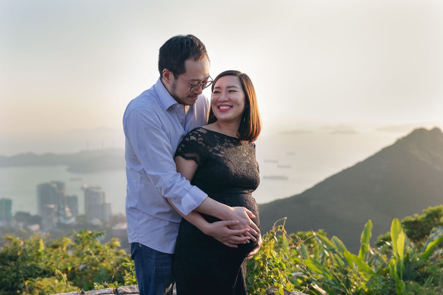 Romantic sunset maternity photos captured with mountain and city skyline backdrop.