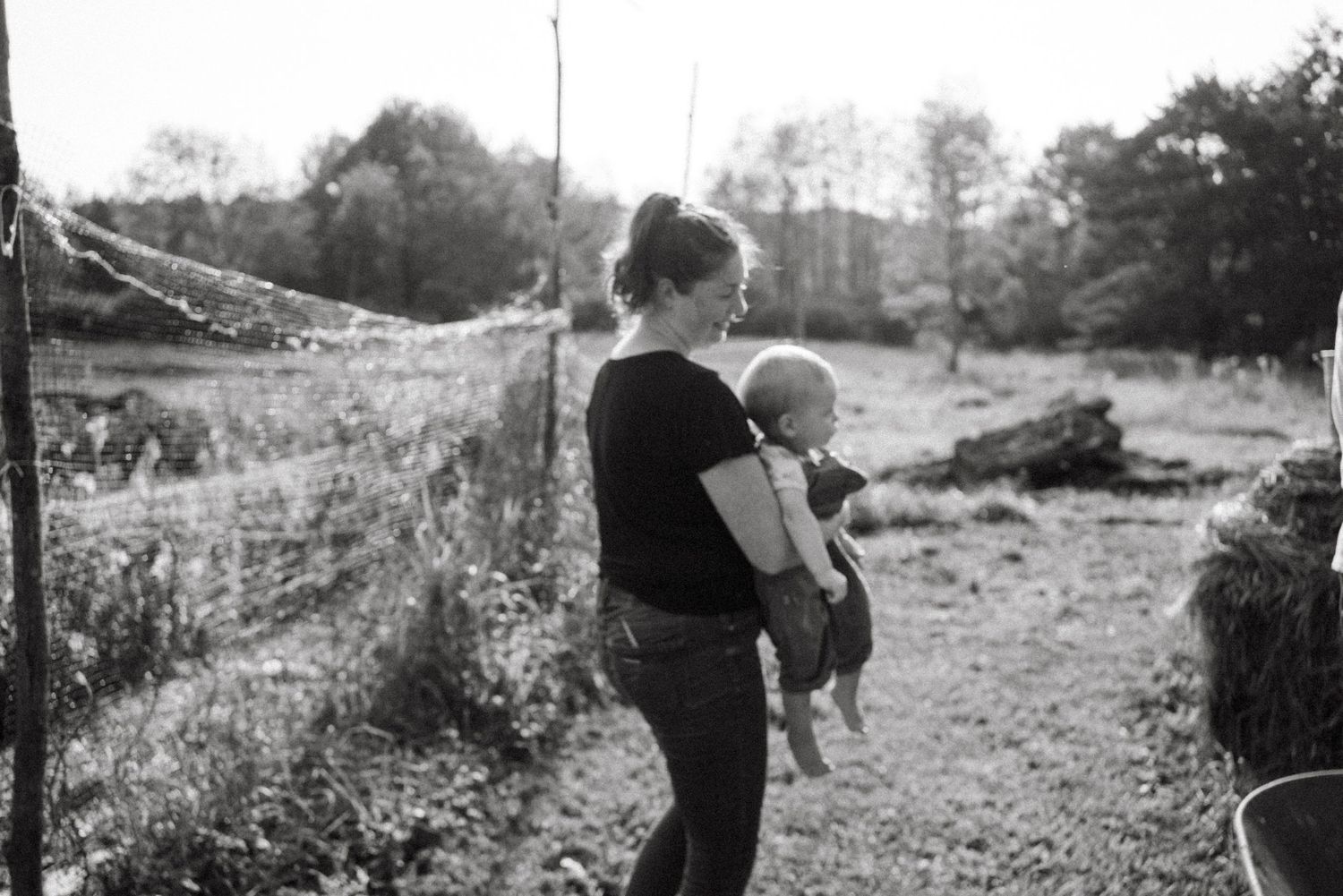 A black and white photo of caretaking in an outdoor farm setting.