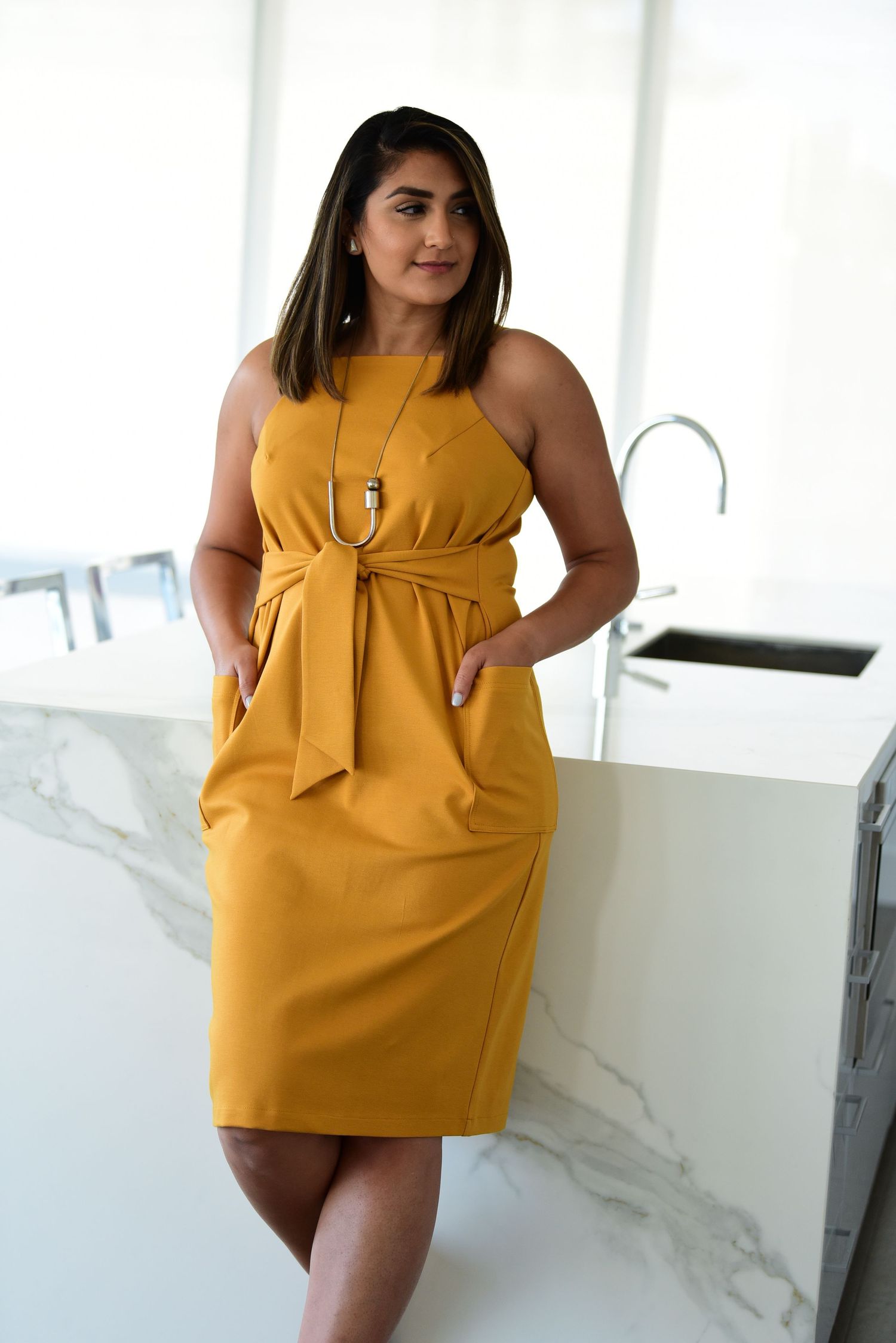 Mustard yellow dress with bow detail shown in fashion photography series.