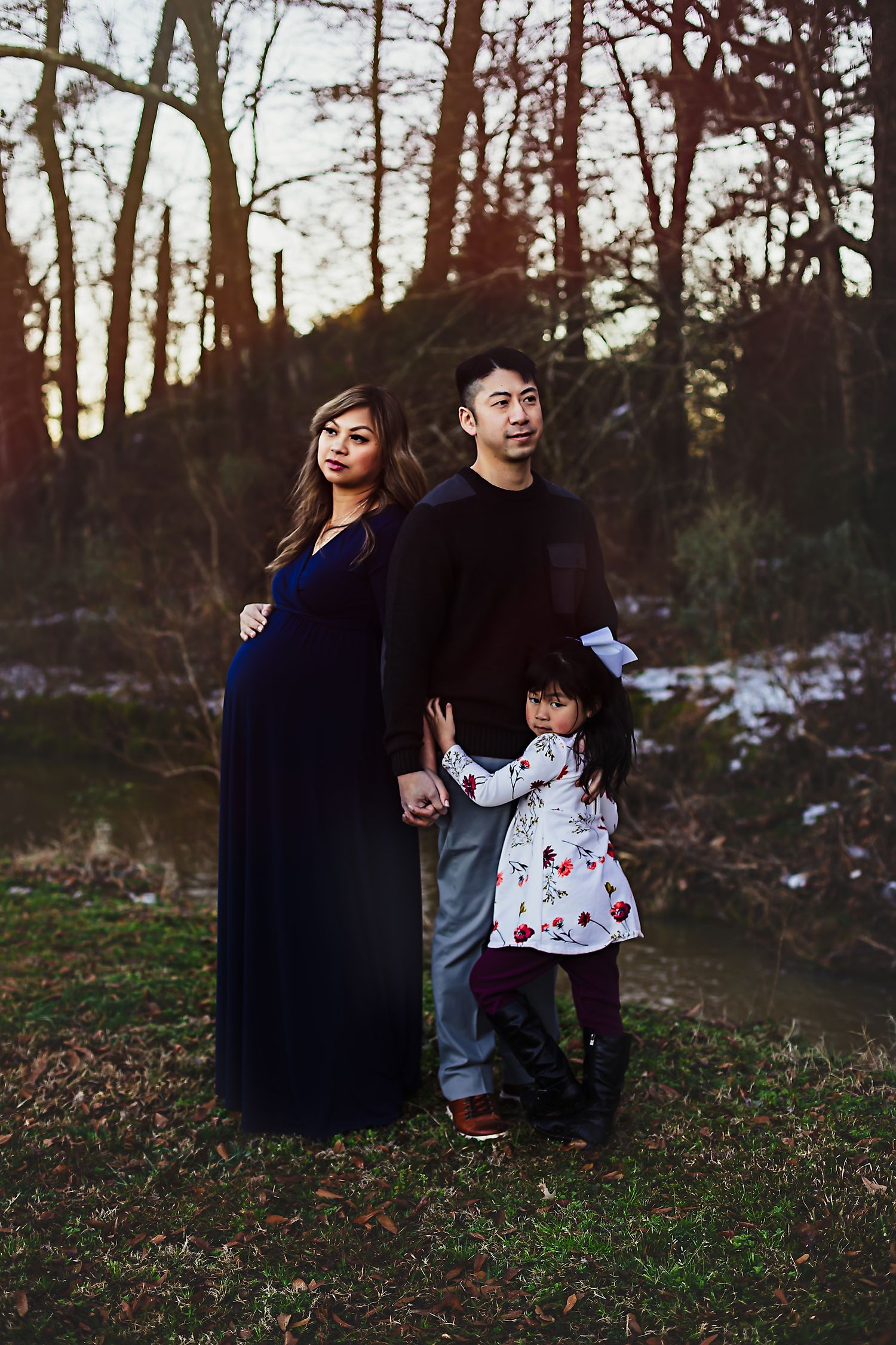 Family portrait in wooded setting at dusk with navy maternity gown.