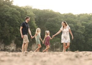 Family walking hand in hand through a scenic field at sunset.