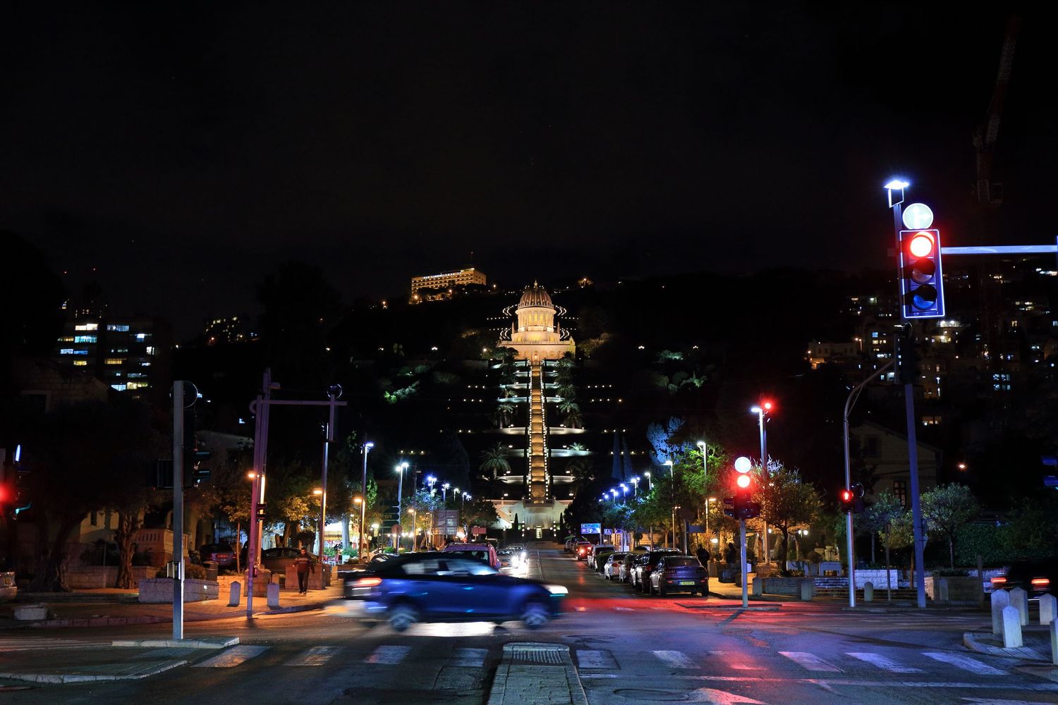Night view of illuminated street leading to the Bahai Gardens in Haifa with car light trails.