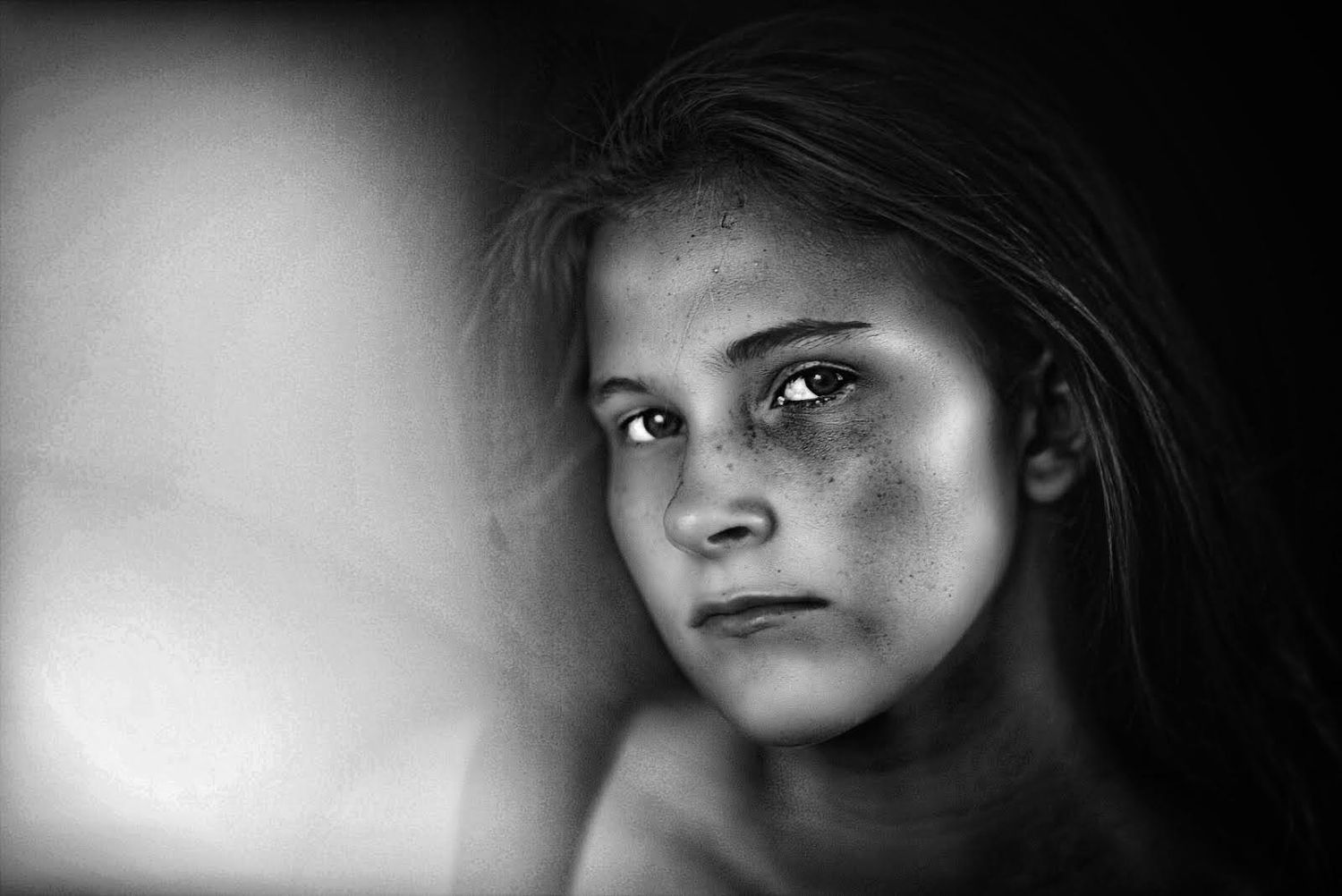 Artistic black and white close-up portrait with dramatic side lighting.