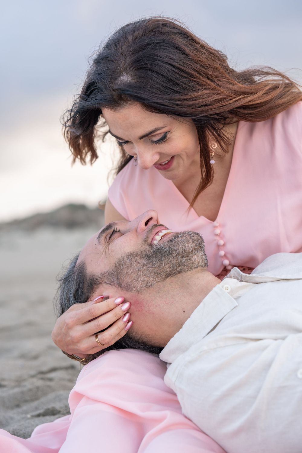 A tender romantic moment shared between a couple on a sandy beach at sunset.