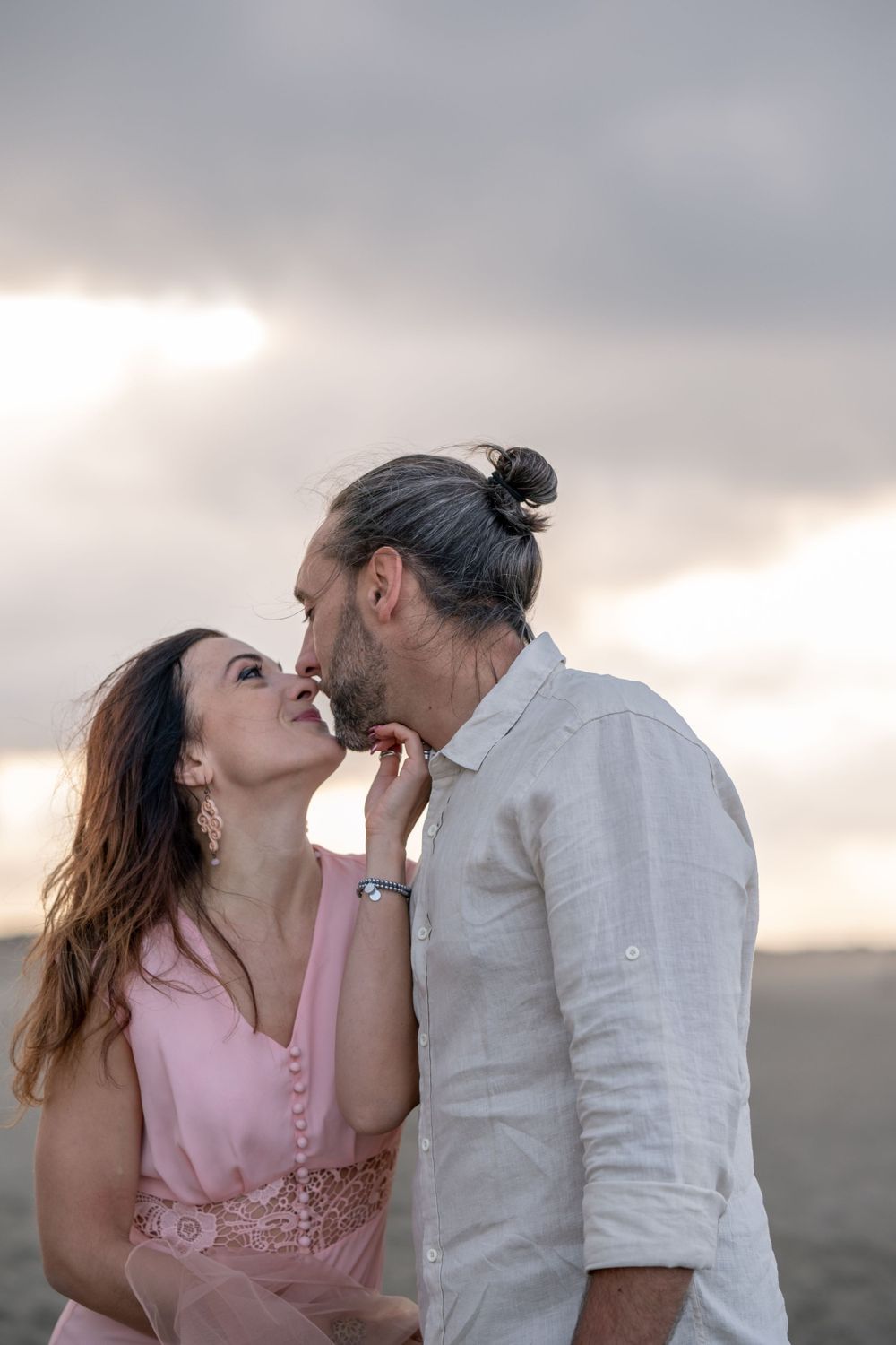 Intimate moment captured against moody beach sunset sky.
