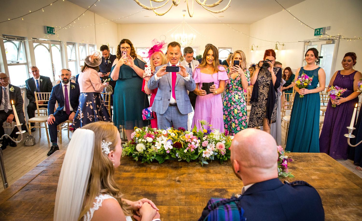 Wedding reception hall decorated with string lights and filled with celebrating guests.