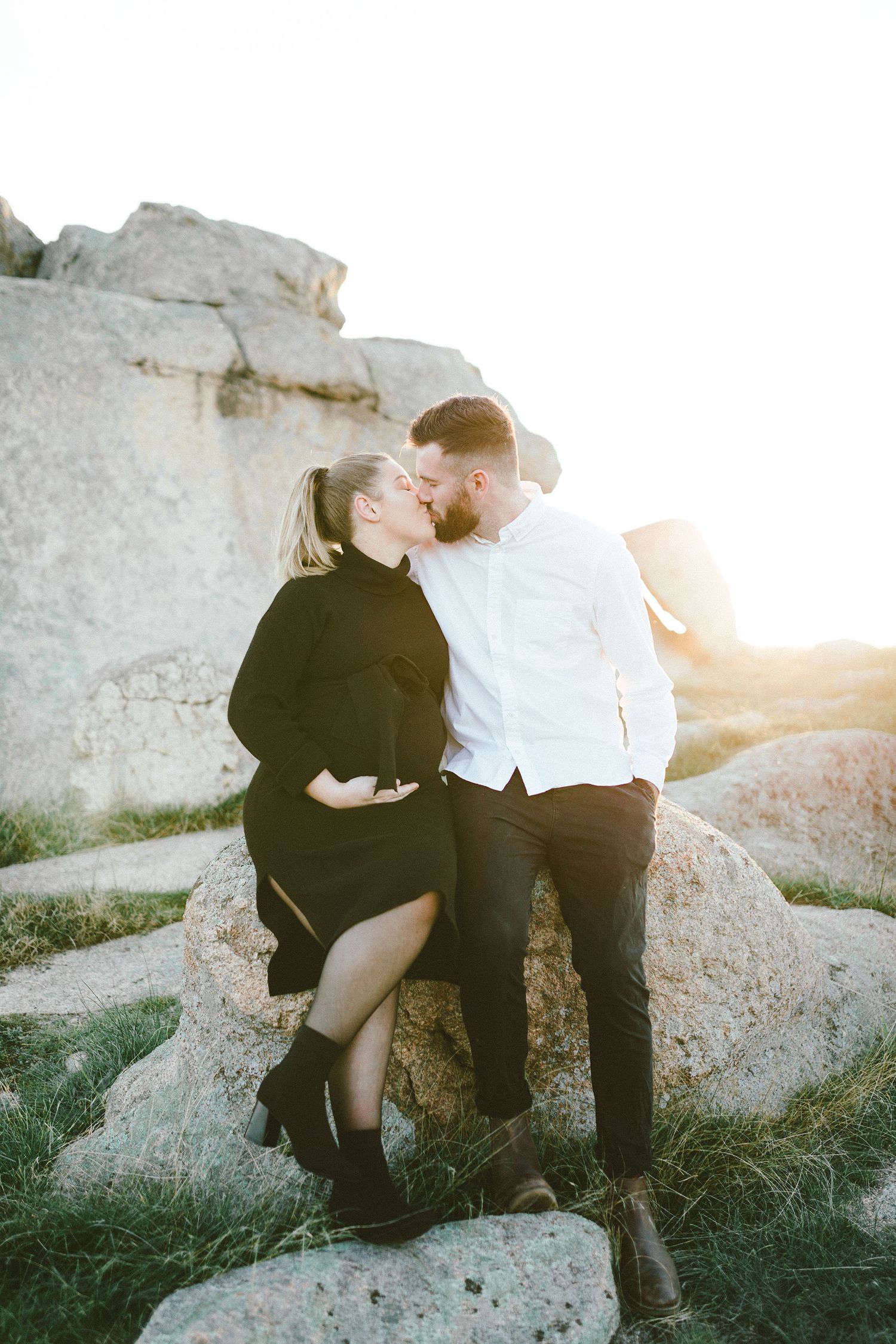 A romantic embrace captured against weathered white rock formations at sunset.
