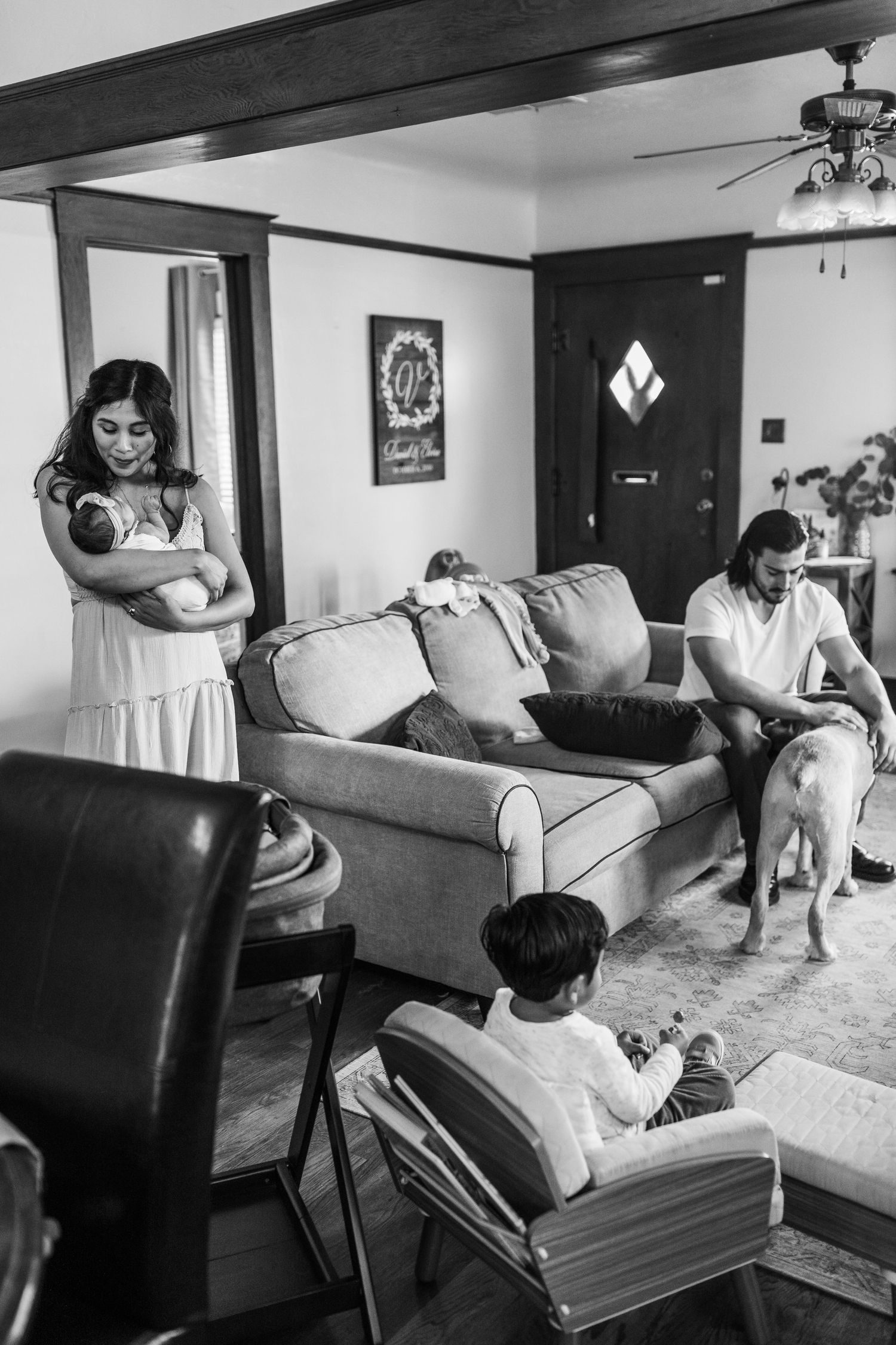 A casual family scene in a living room with people relaxing on couches and chairs in black and white.